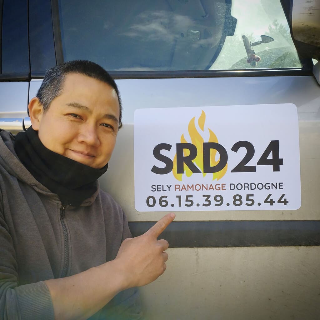 Sayeen, foncdateur de SRD24 SELY Ramonage Dordogne, présentant le logo aimanté sur son véhicule d'intervention à Prigonrieux près de Bergerac.